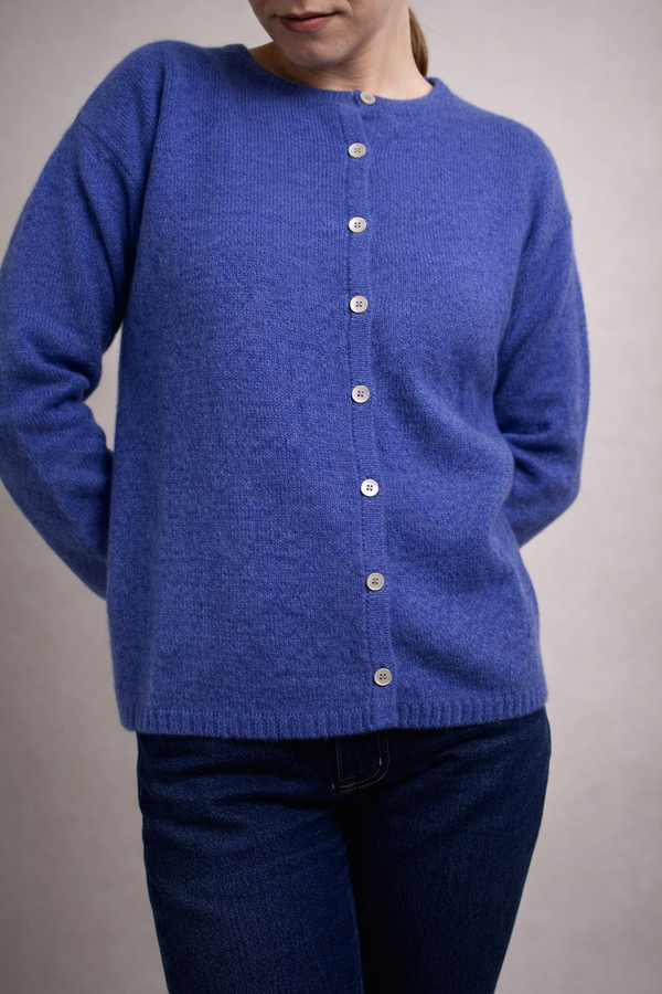 half british lambswool crew neck cardigan in periwinkle blue, worn buttoned to the neck showing the soft knit texture