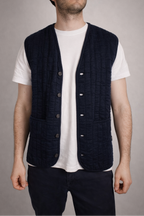 half british cotton quilted knitted gilet in navy, worn open over a white t-shirt showing the quilted knit panels and button front