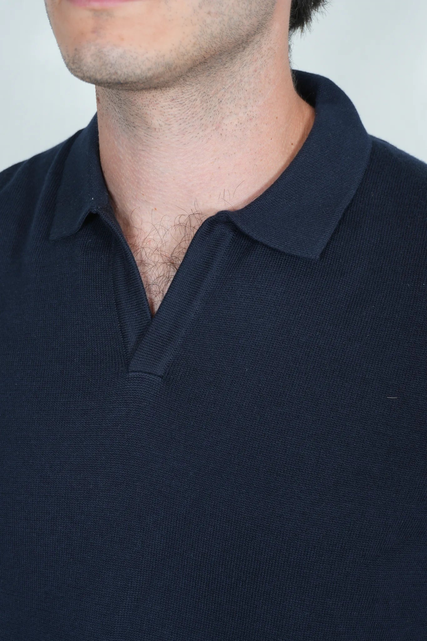 Close-up of a man wearing a dark navy blue polo shirt, showing the collar and upper chest area.
