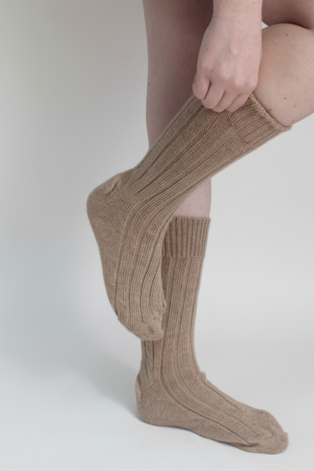 half british alpaca lounge socks in fawn, worn and gently adjusted to highlight the ribbed knit texture and soft alpaca fibre against a neutral background