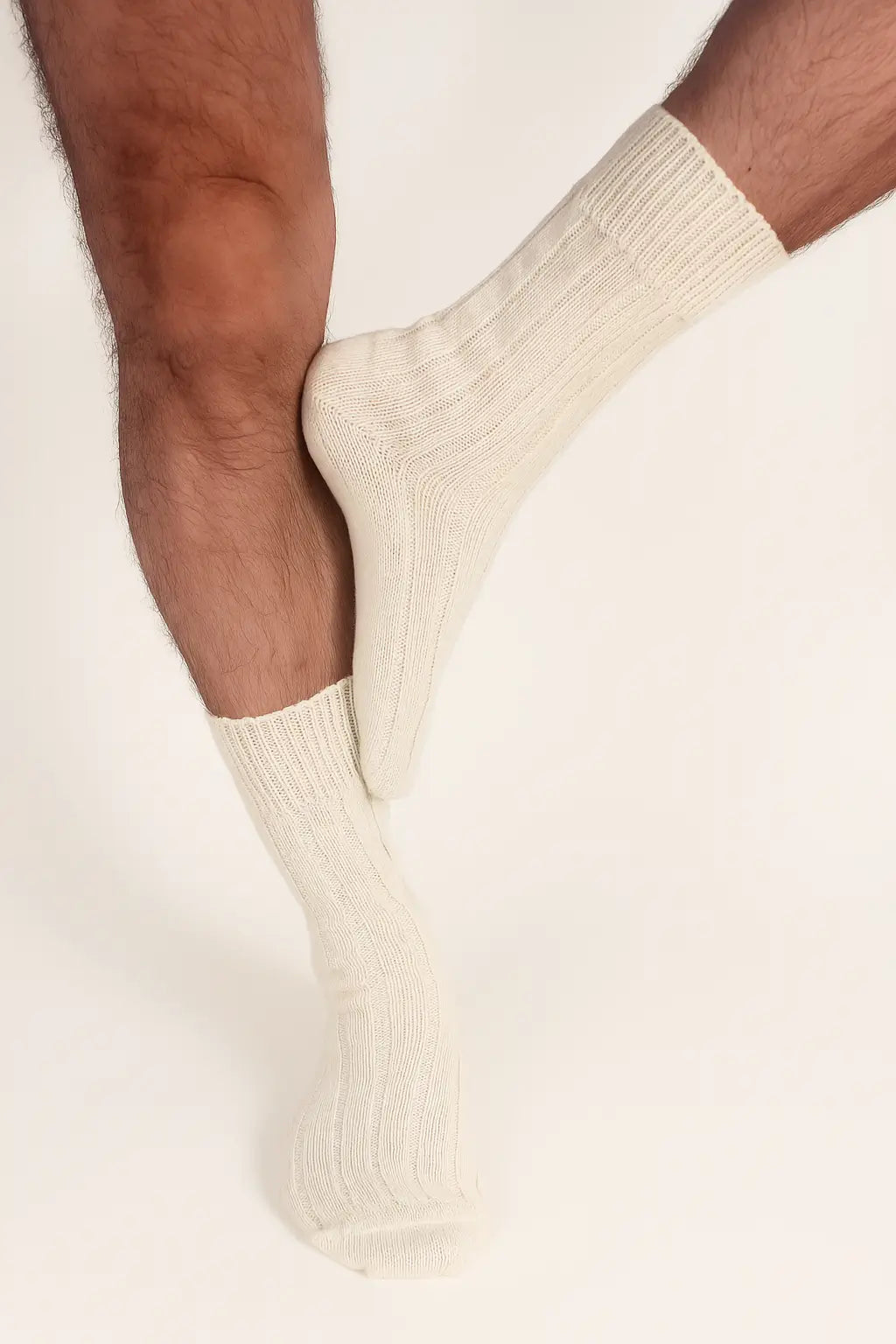 half british alpaca lounge socks in cream, worn with legs crossed to highlight the ribbed knit texture and soft alpaca fibre against a light background