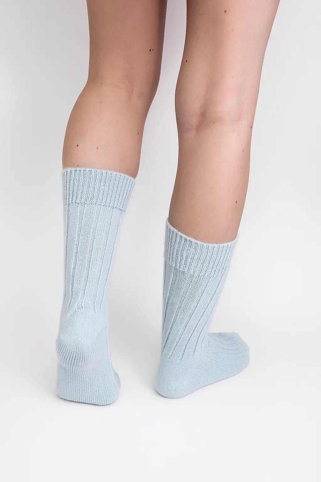 half british alpaca lounge socks in baby blue, worn to show the ribbed knit detail and cosy alpaca texture against a background
