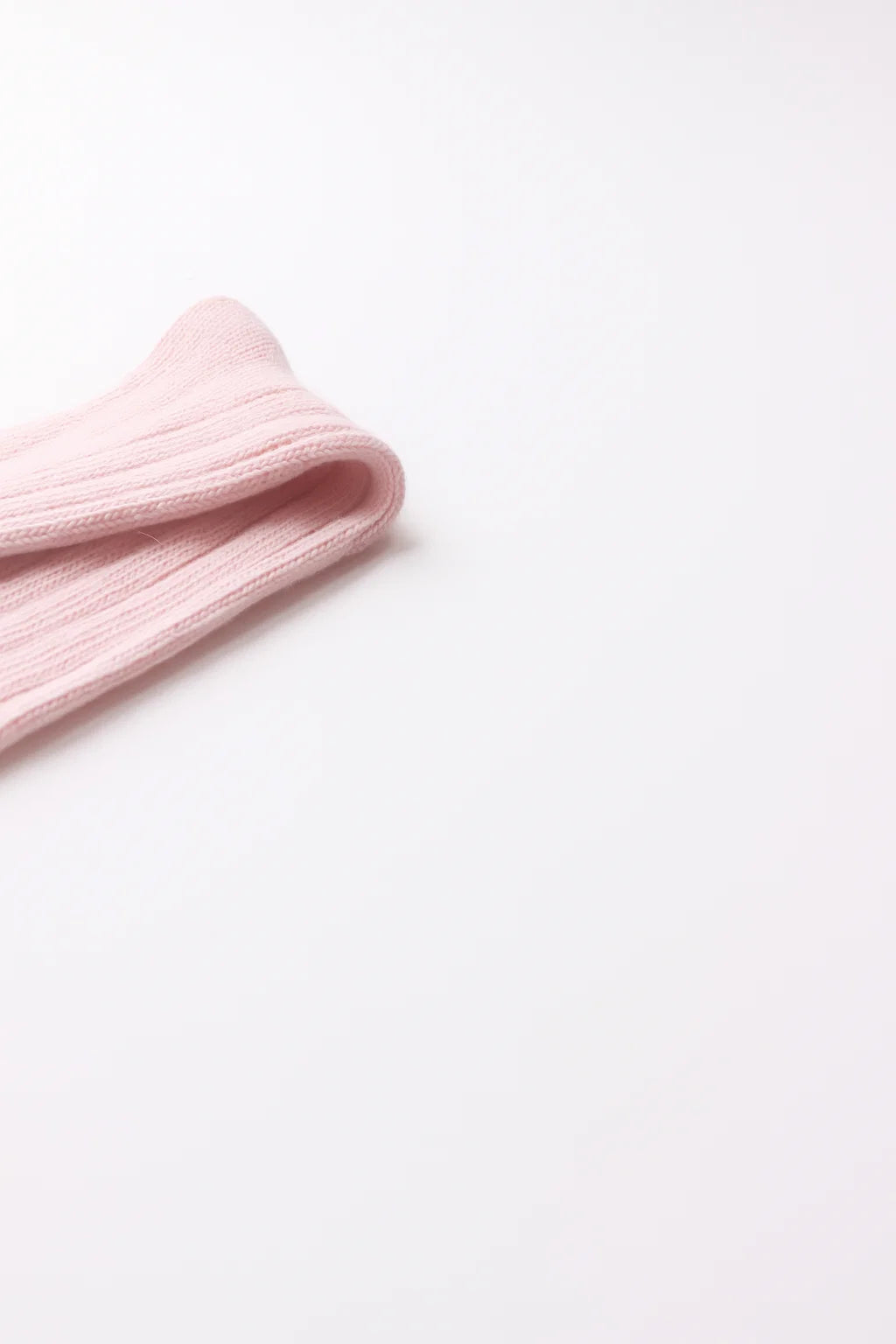 half british alpaca lounge sock in pink, folded neatly on a background showing the ribbed knit pattern and soft alpaca texture